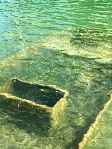Opuszczony łodzi w zalane kamieniołomy niebieski kryształ wodą. Nurek witryny z świeże niebieski i czystej wody dla nurków niewiele opuszczony umywalka łodzi w jeziorze. Floreffe, Belgia. - Zdjęcie, obraz