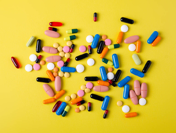 Pills capsules medicine health on yellow background top view - 写真・画像