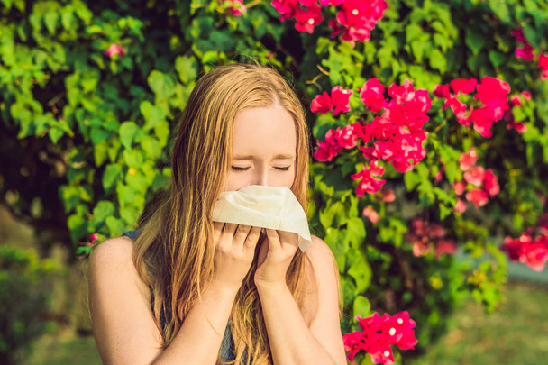 Pollen allergy concept. Young woman is going to sneeze. Flowering trees in background - Foto, afbeelding