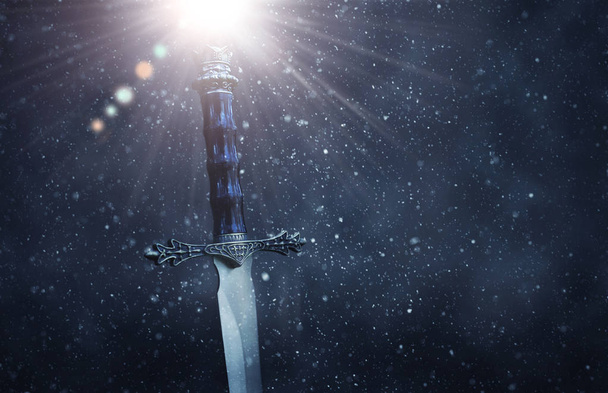 mysterious and magical photo of silver sword over gothic snowy black background. Medieval period concept - Foto, Bild