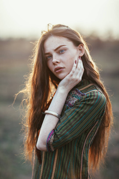 Fashion portrait of young hippie woman at sunset posing on nature background - Фото, изображение