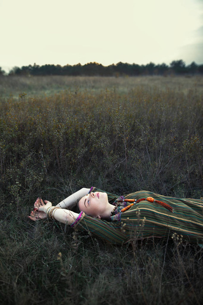 Beautiful hippie woman lying on grass relaxing on summer field. Carefree concept - Φωτογραφία, εικόνα