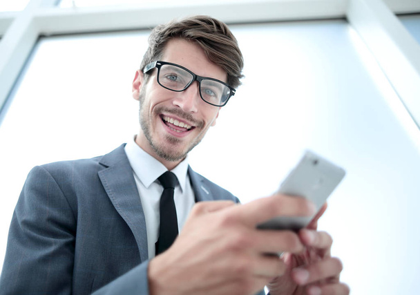 businessman looking at the camera and holding the phone in his h - Фото, изображение