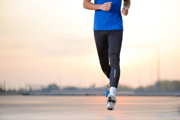 Gros plan sur les jambes des hommes sportifs qui courent au coucher du soleil. Mode de vie sain et concept sportif
. - Photo, image