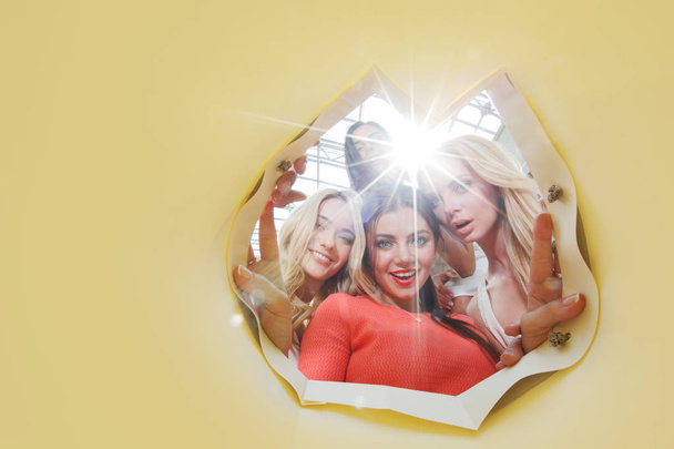 Beautiful young women looking inside bag , yellow background with copy space for text - Photo, Image