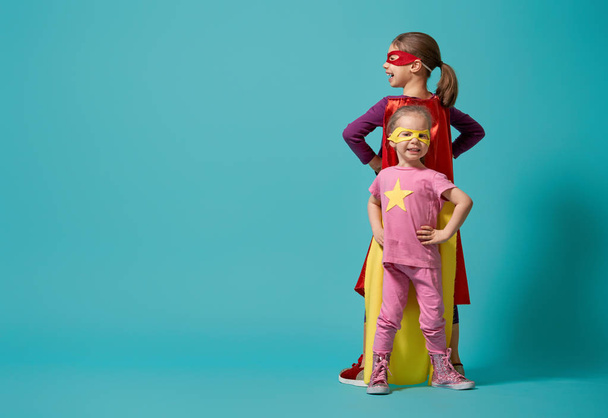 Little children are playing superhero. Kids on the background of bright wall. Girl power concept. - Foto, Imagen