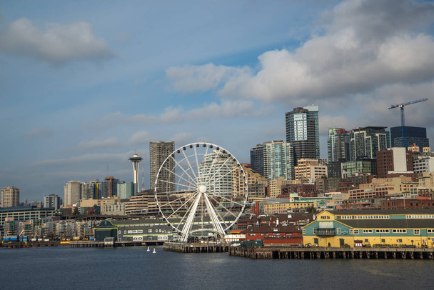 Lungomare e skyline di Seattle, con lo Space Needle che mostra attraverso i raggi della ruota panoramica Great Wheel in primo piano. Immagine colorata con luce dorata nel tardo pomeriggio
. - Foto, immagini