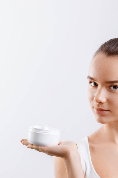 Beauty Concept. woman holds a cream in her hand and spreads it on her face to moisturize her skin and wrinkle from impurities. body care, skincare.Taking good care of her skin - Valokuva, kuva
