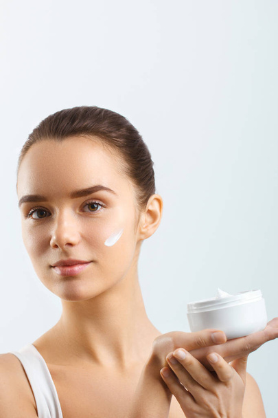 Skincare. Beauty Concept. Young pretty woman holding cosmetic cream - Foto, afbeelding