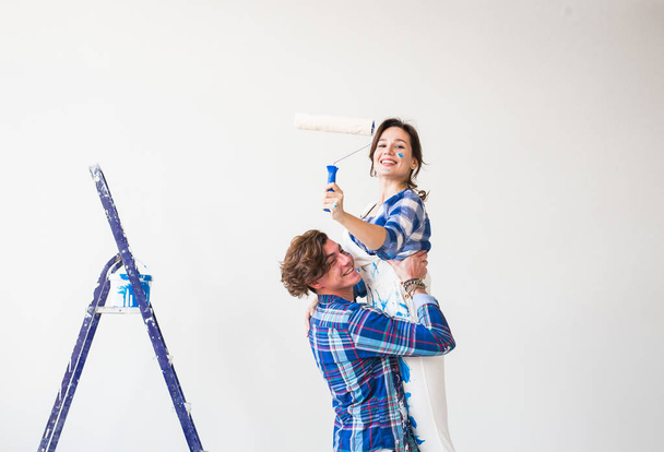 Renovación, redecoración y concepto familiar: el joven sostiene a la joven en sus brazos durante la renovación en el apartamento
 - Foto, imagen