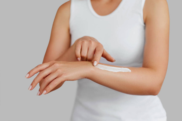 Closeup shot of woman hands holding cream and applying moisturizing hand cream. Beautiful female hands with cream. Hand Skin Care. A woman uses body lotion on your arms. Beauty And Body Care Concept  - Φωτογραφία, εικόνα