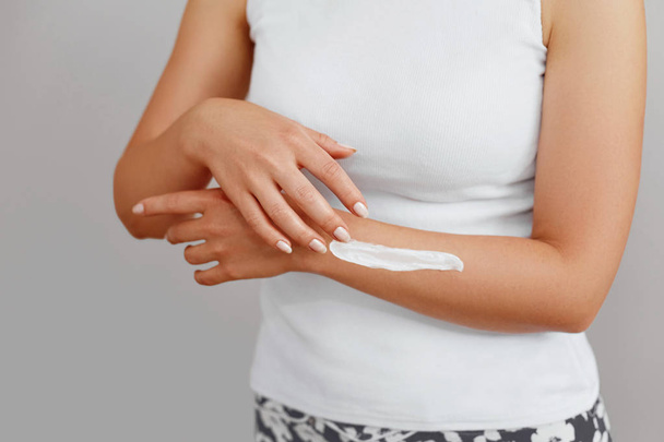 Closeup shot of woman hands holding cream and applying moisturizing hand cream. Beautiful female hands with cream. Hand Skin Care. A woman uses body lotion on your arms. Beauty And Body Care Concept  - Foto, imagen