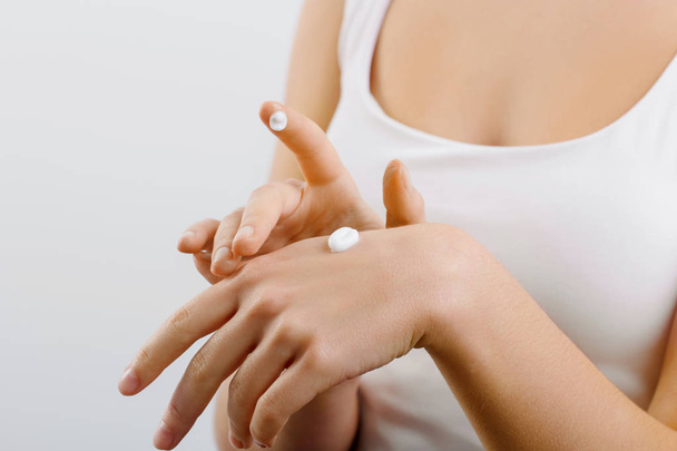 Closeup shot of woman hands holding cream and applying moisturizing hand cream. Beautiful female hands with cream. Hand Skin Care. A woman uses body lotion on your arms. Beauty And Body Care Concept  - Photo, Image
