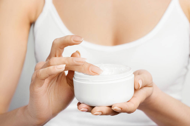 Closeup shot of woman hands holding cream and applying moisturizing hand cream. Beautiful female hands with cream. Hand Skin Care. A woman uses body lotion on your arms. Beauty And Body Care Concept  - Foto, Imagen