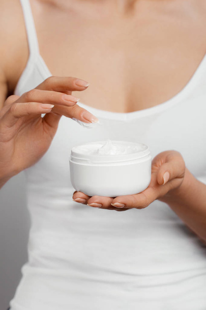 Closeup shot of woman hands holding cream and applying moisturizing hand cream. Beautiful female hands with cream. Hand Skin Care. A woman uses body lotion on your arms. Beauty And Body Care Concept  - Φωτογραφία, εικόνα
