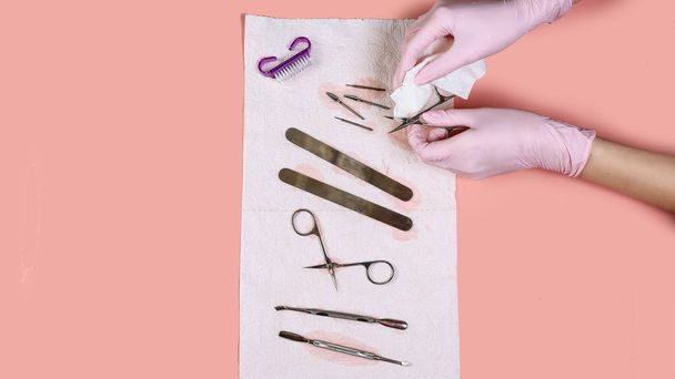 Manicure tool in the hands of the master. set of manicure accessories on pink background top view. flat lay composition with copy space. the concept of personal protective equipment. - Photo, Image