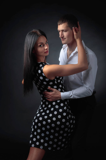 Młoda piękna kobieta polka dot strój i człowiek w białej koszuli tańczyć tango. Para zakochanych, taniec w Studio. - Zdjęcie, obraz