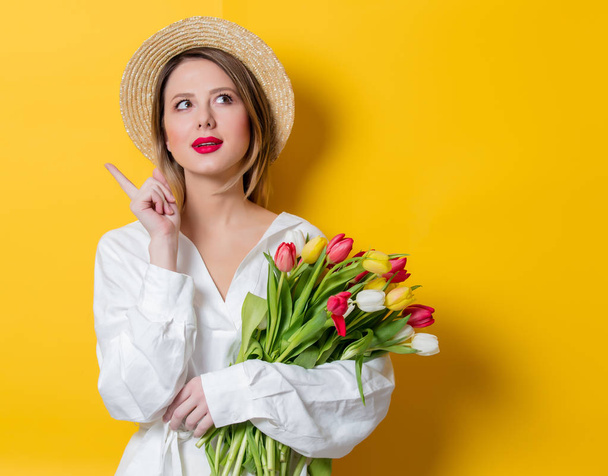 woman in white shirt and hat with fresh springtime tulips - Foto, Bild