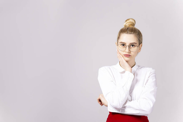 Studio shot of gorgeous young blonde business woman wearing round eyeglasses, white cotton blouse top & sexy tight red skirt. Gray isolated background, copy space, close up, portrait - Photo, image