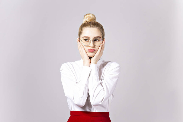 Studio shot of gorgeous young blonde business woman wearing round eyeglasses, white cotton blouse top & sexy tight red skirt. Gray isolated background, copy space, close up, portrait - Foto, Imagem