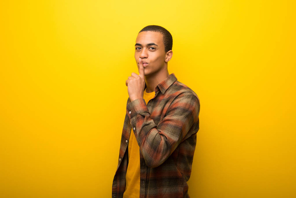 Молодий афроамериканець людиною на яскраві жовтому тлі показ ознакою закриття рот і мовчання жест - Фото, зображення