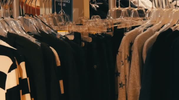 Stijlvolle kleren opknoping in rij op hangers in een kledingwinkel in een winkelcentrum. - Video