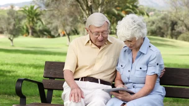 Old couple using a tablet on a bench - Filmagem, Vídeo