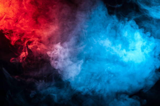 Clouds of isolated colored smoke: blue, red, orange, pink; scrolling on a black background in the dark close up. - Photo, Image