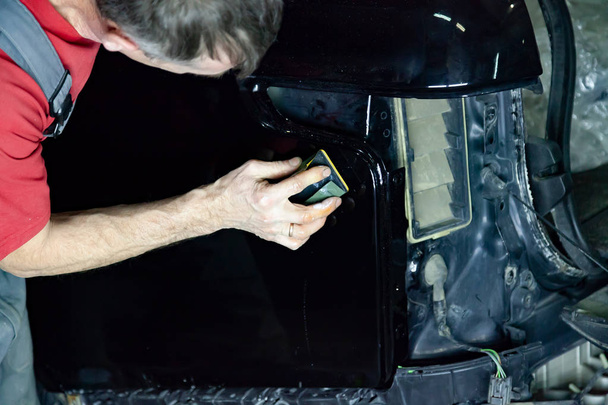 Polerka obejmuje ciało pojazdu z specjalnym woskiem do ochrony samochodu przed drobne zarysowania i uszkodzenia, pocieranie powierzchni czarnych Suv z gąbką. - Zdjęcie, obraz