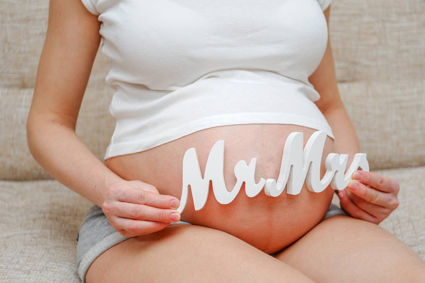 Uma menina grávida em uma camiseta mostra que ela está esperando um menino e uma menina
. - Foto, Imagem