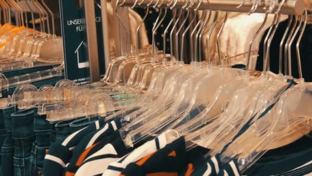 Modische Jugendkleidung hängt an Kleiderbügeln in einem Bekleidungsgeschäft in einem Einkaufszentrum. - Filmmaterial, Video