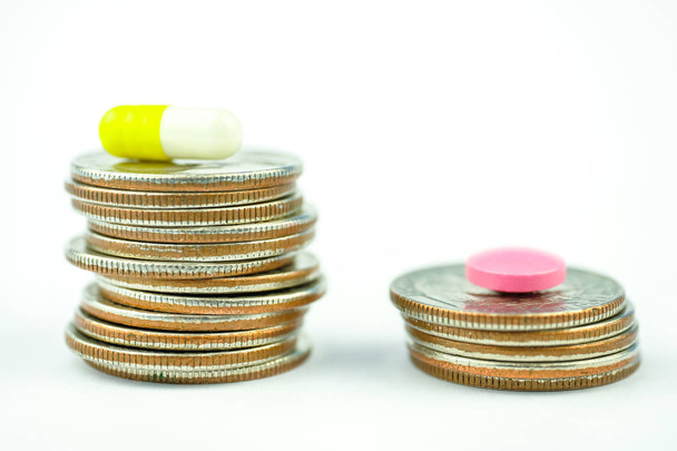 Comparaison de concepts et coût élevé des médicaments. Pilule rose et capsule sur les piles de pièces sur fond blanc
. - Photo, image