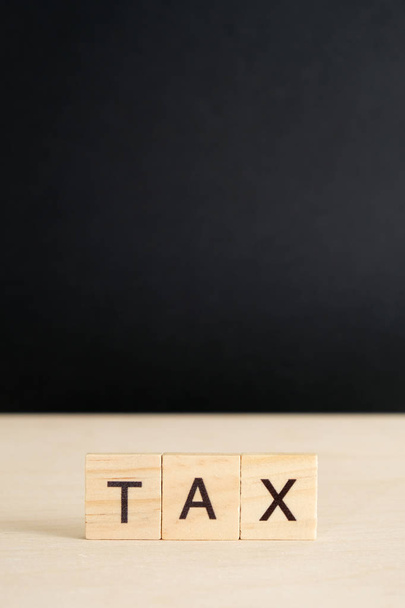 The word "tax" on a wooden and black background with copy space. Vertically. Mock up. - Foto, Imagem