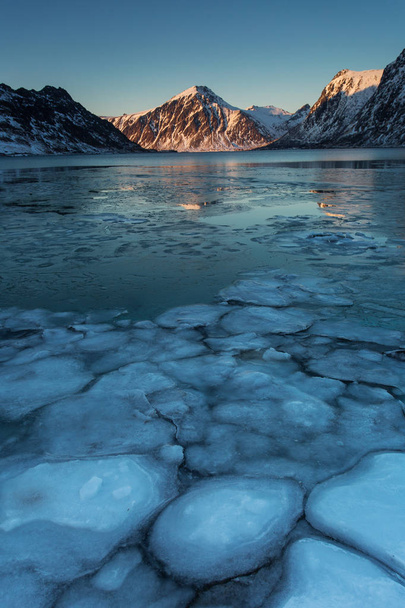 Widok piękny krajobraz z kostkami lodu w wodzie i góry w tle. Lofotach, Norwegia - Zdjęcie, obraz