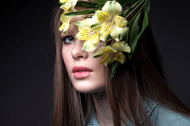 Beautiful teen girl. With flowers and beautiful make-up on a dark gray background. - Photo, Image
