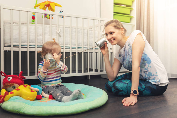 mãe e criança brincando com lata pode telefone em casa. conceito de falar e ouvir
 - Foto, Imagem