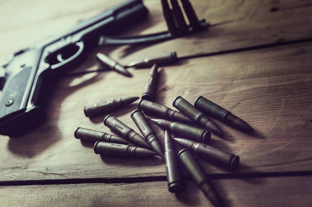 пистолет и боеприпасы на деревянном столе
 - Фото, изображение