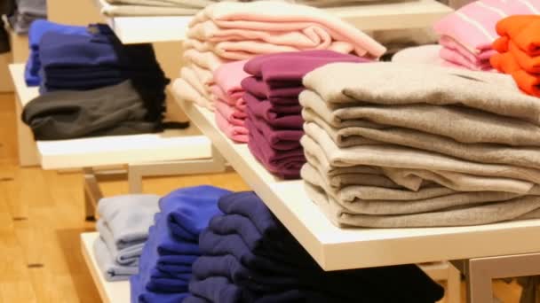 Nürnberg, Duitsland - 3 December 2018: Stijlvolle kleding gestapeld op de planken in rij op hangers in een kledingwinkel in een winkelcentrum. - Video