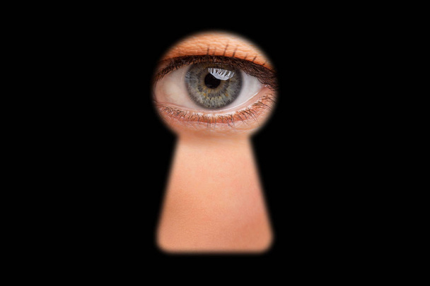 Henkilön silmä katselee avaimenreiästä ovissa
 - Valokuva, kuva