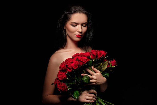 beautiful young woman with a large bouquet of red roses - Photo, Image