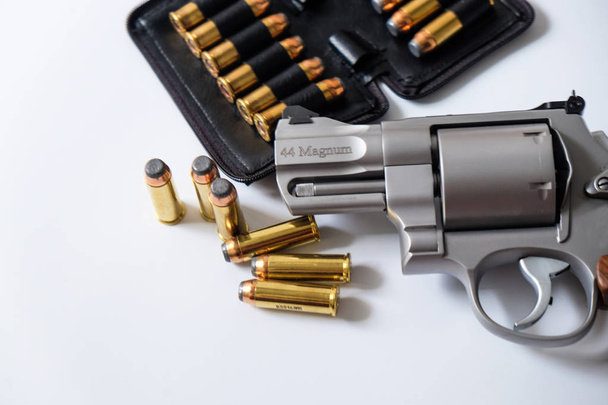 .44 magnum revolver pistool arm met metalen kogel in leerzak geïsoleerd op witte achtergrond - Foto, afbeelding