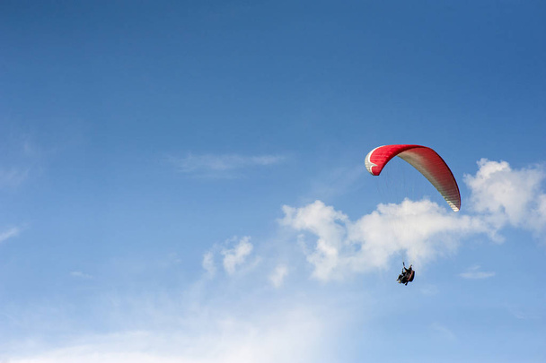 Alone paraglider flying in the blue sky against the background of clouds. Paragliding in the sky on a sunny day. - Photo, image