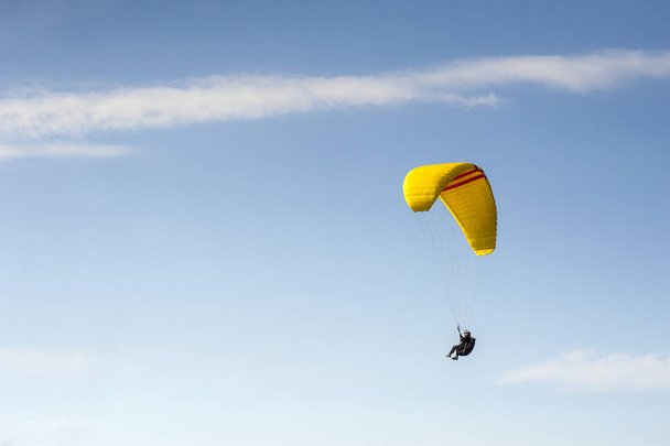 Sám padákové létání na modré obloze na pozadí mraků. Paragliding na obloze za slunečného dne. - Fotografie, Obrázek