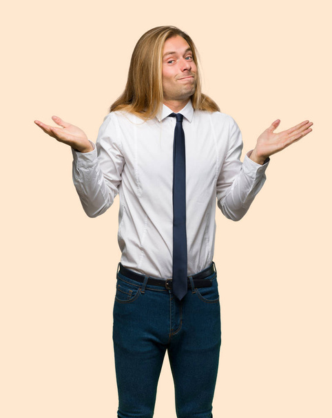 Blond zakenman met lange haren onbelangrijk gebaar maken terwijl het opheffen van de schouders op geïsoleerde achtergrond - Foto, afbeelding