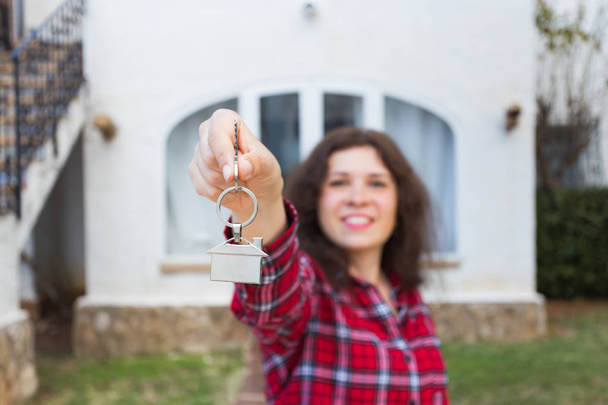 Real estate and property concept - Happy young woman in front of new home with new house keys - Photo, Image