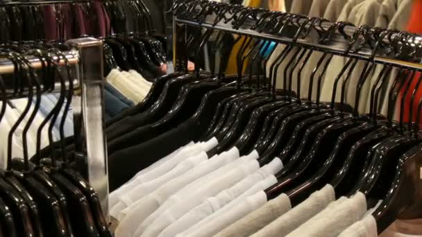 Stylowe ubrania wiszące w wierszu na wieszakach w Sklep odzieżowy w centrum handlowym. - Materiał filmowy, wideo