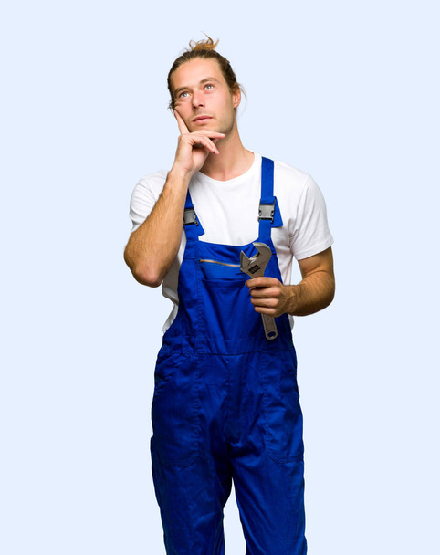 Workman thinking an idea while looking up on isolated background - Photo, image