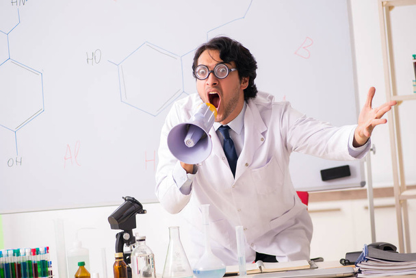 Joven químico divertido delante de la pizarra blanca
  - Foto, Imagen