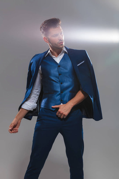 портрет джентльмена в блакитному костюмі на плечі і дивиться вниз в сторону, стоячи на світло-сірому фоні
 - Фото, зображення
