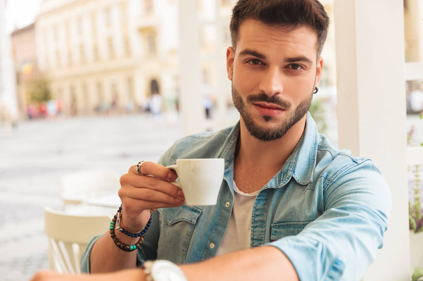 Portret van aantrekkelijke casual man dragen denim shirt met een koffiepauze in de stad  - Foto, afbeelding